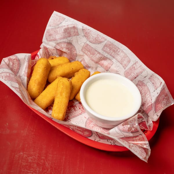 Golden fried cheese sticks in a red basket with That Chicken Place branded paper and a side of dipping sauce.